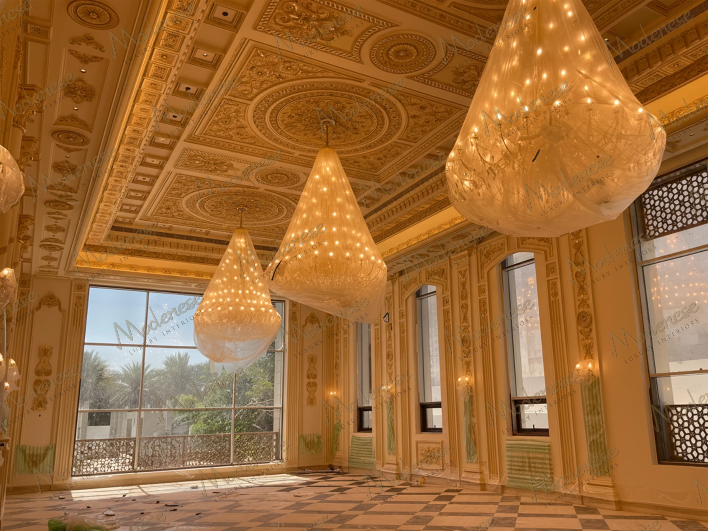 Grand chamber in Saudi Arabia King's Palace featuring wrapped chandeliers, detailed coffered ceiling, and tall windows overlooking palm trees