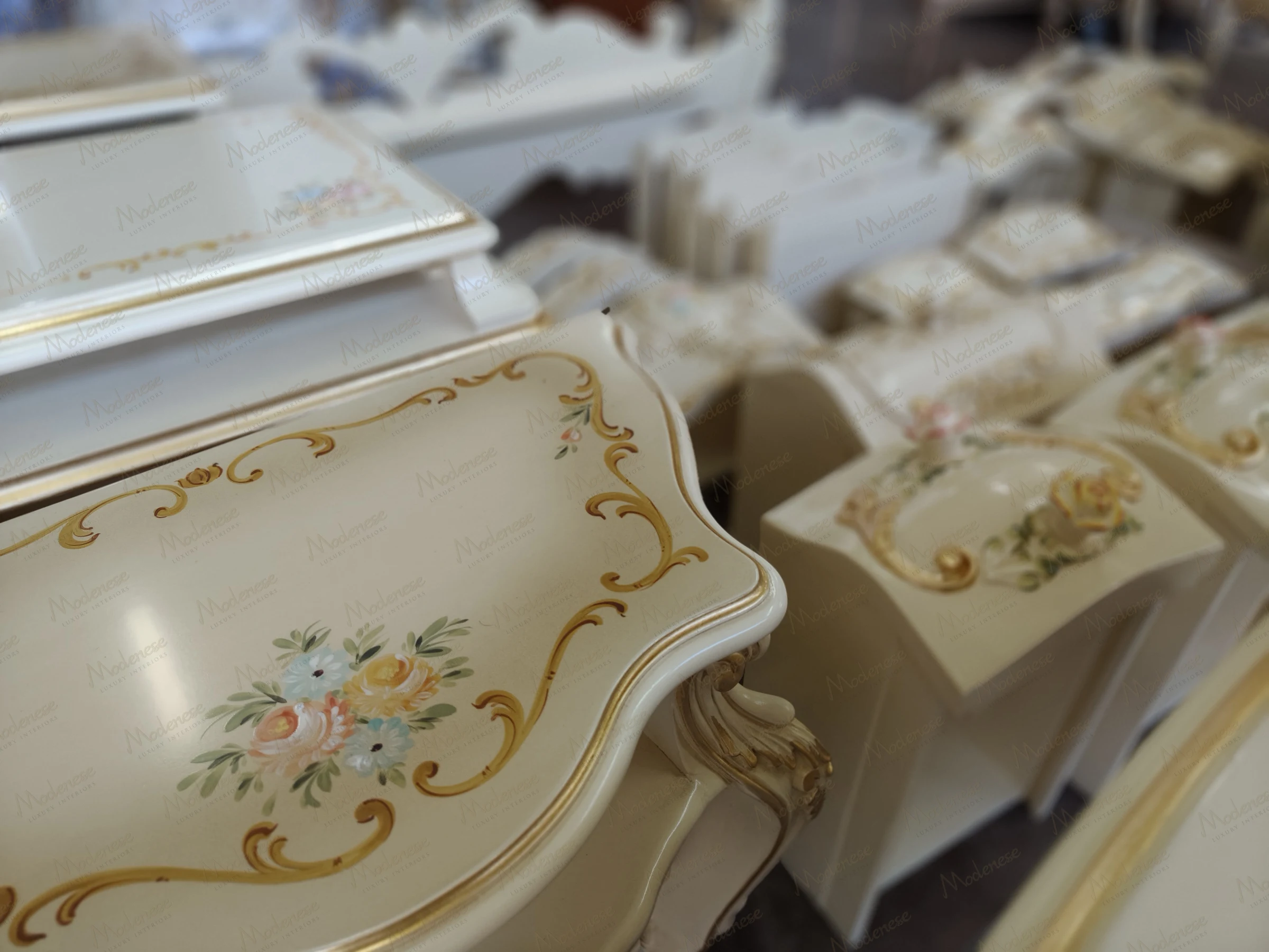 Close-up of hand-painted Milan furniture featuring floral and gold scroll motifs on cream lacquered wood surfaces
