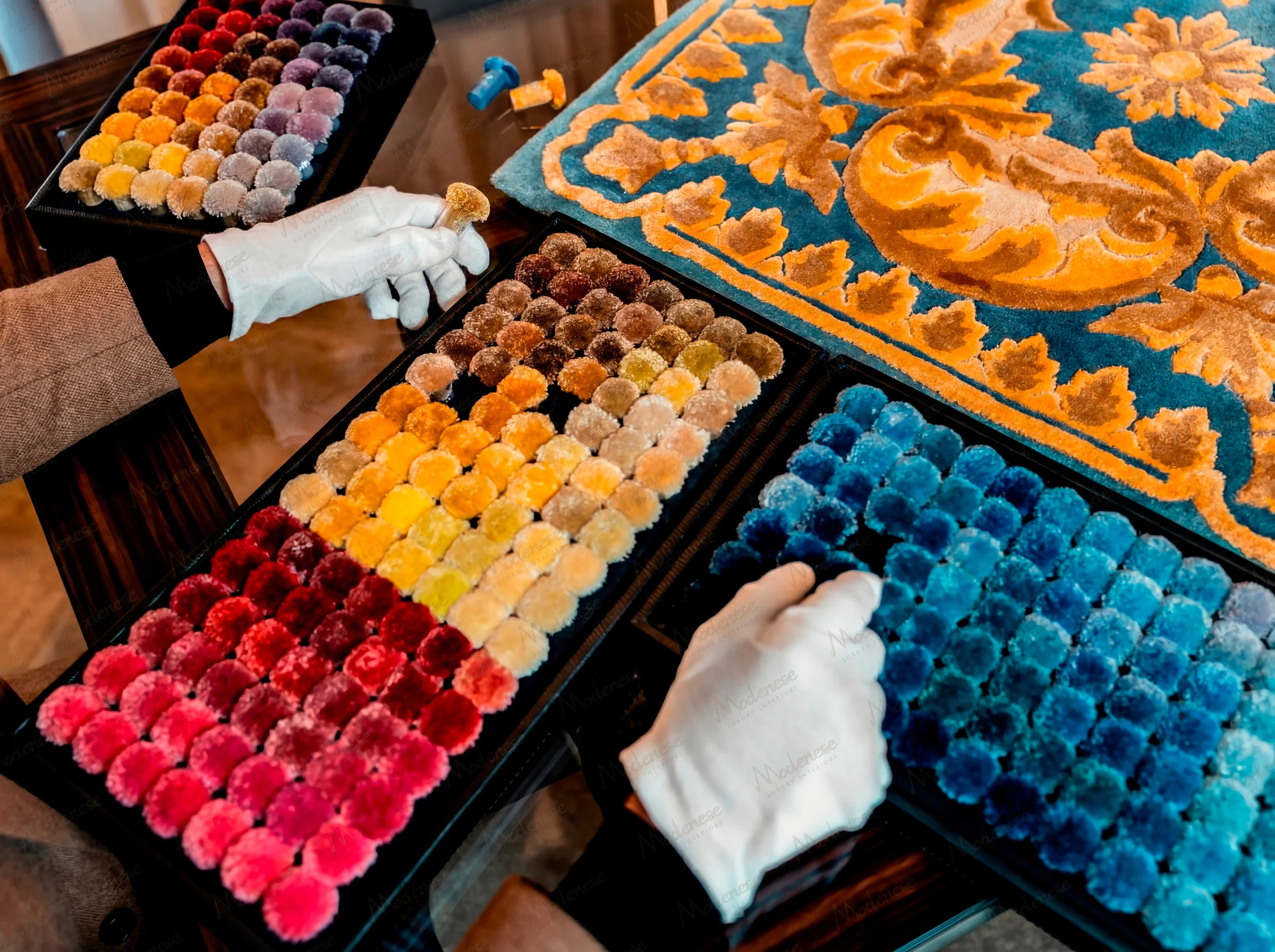 Design studio with custom luxury carpet samples, hand-drawn patterns, artisanal craftsmanship, and bespoke rug design by Modenese Luxury Interiors